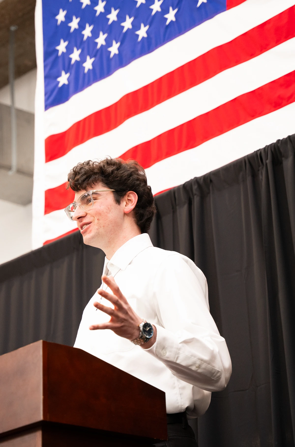 A student speaks on stage beneath the American flag